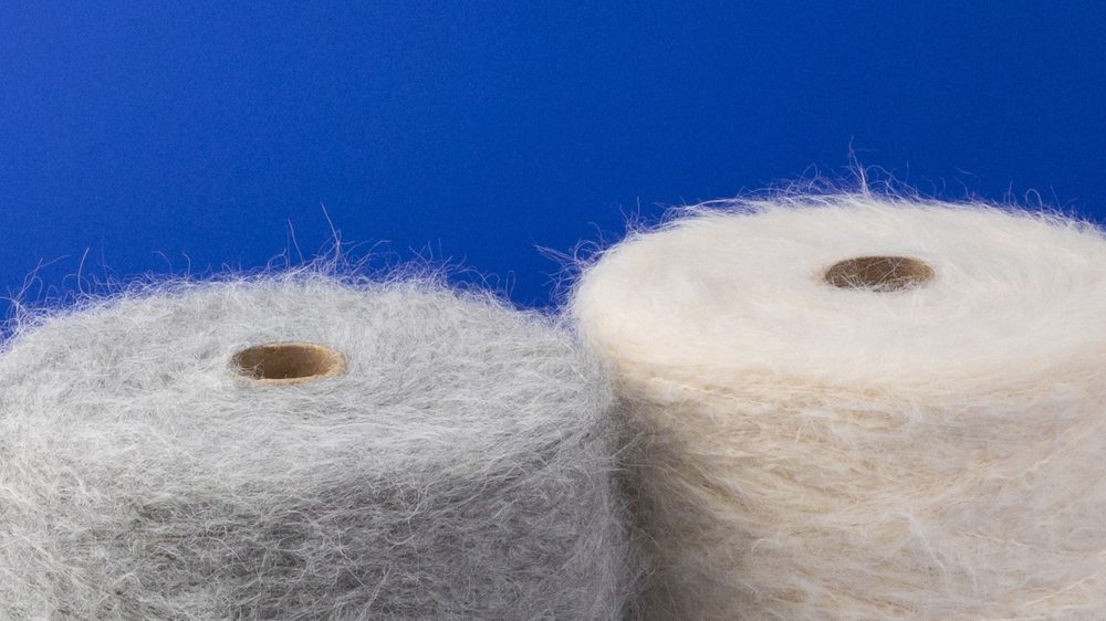 Conos de hilado de alpaca brushed sobre fondo azul
